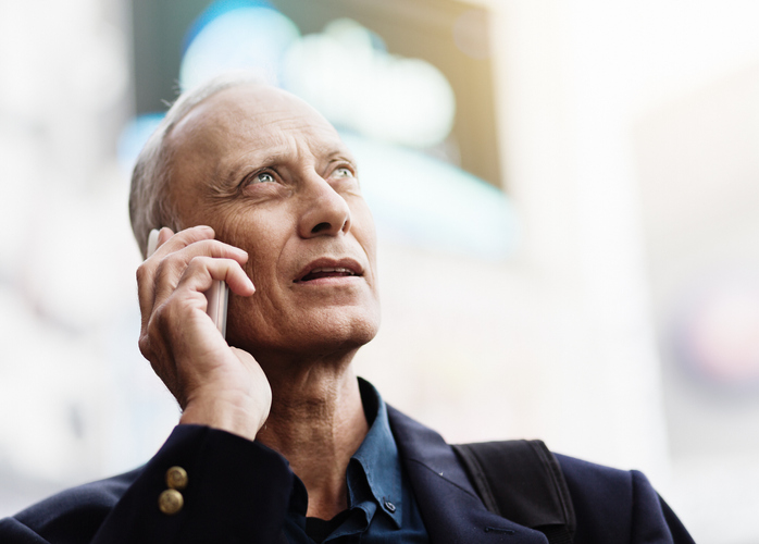 Businessman has a difficult conversation on his phone in the street.